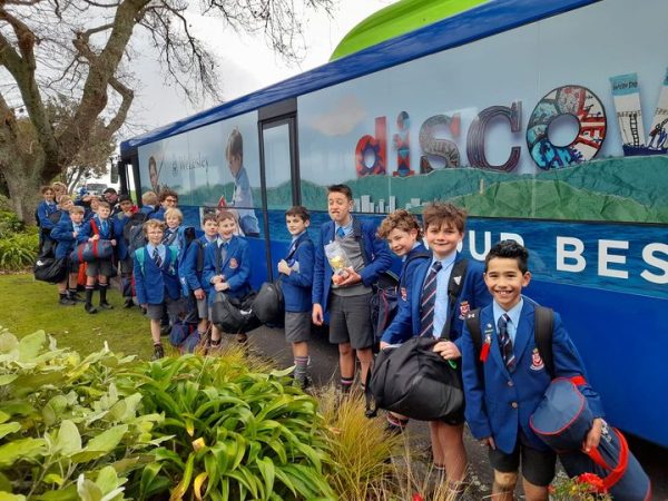 Wellesley College students in uniform standing next to the school bus smiling