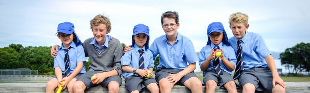 A few Wellesley College boys in uniform standing together, smiling at the camera