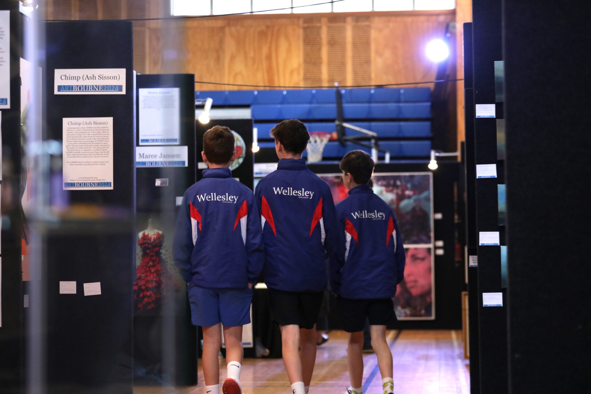 Students at Wellesley College walk around the Days Bay art exhibition, observing and discussing the artwork on display