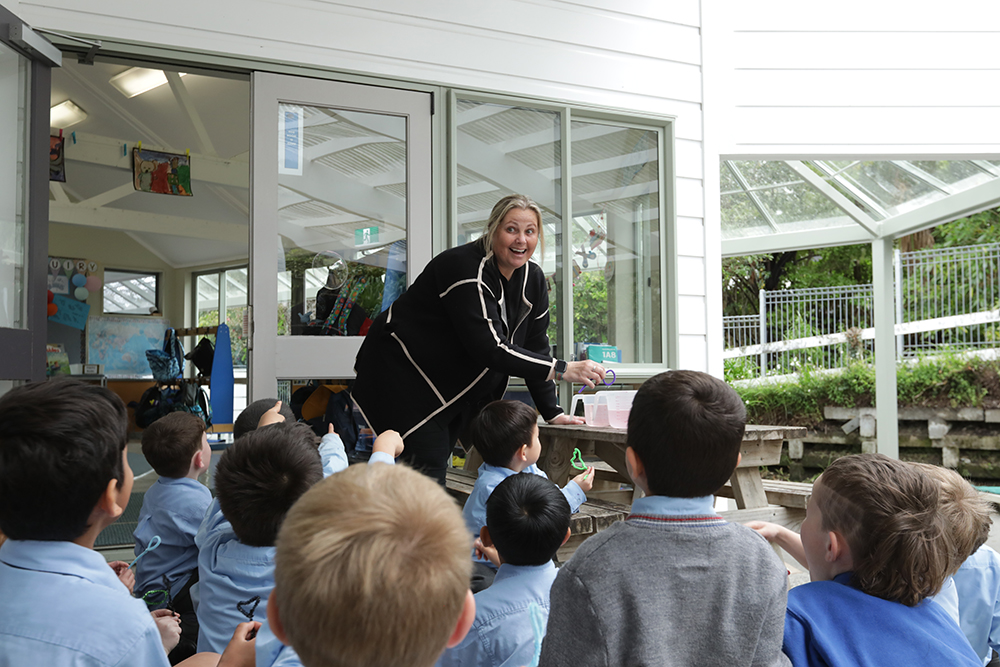 A teacher is teaching a group of young boys, who are seated and engaged as they listen and take part in the lesson