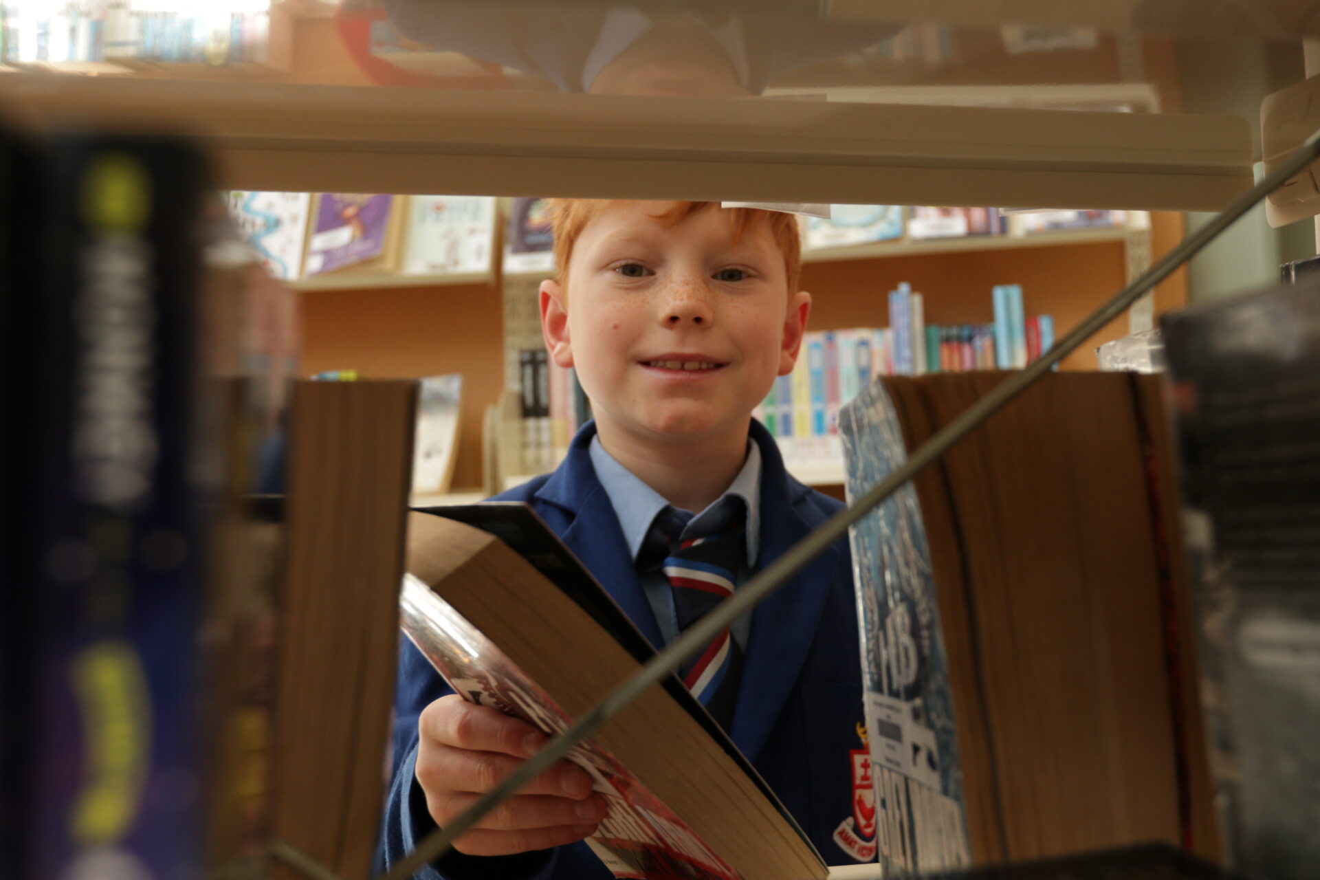 A Wellesley student in the library reaching for a book from a shelf