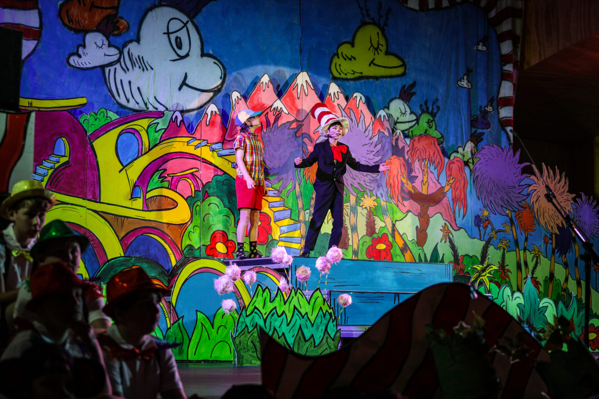 A student dressed as the Cat in the Hat performing on stage in a school production of Seussical