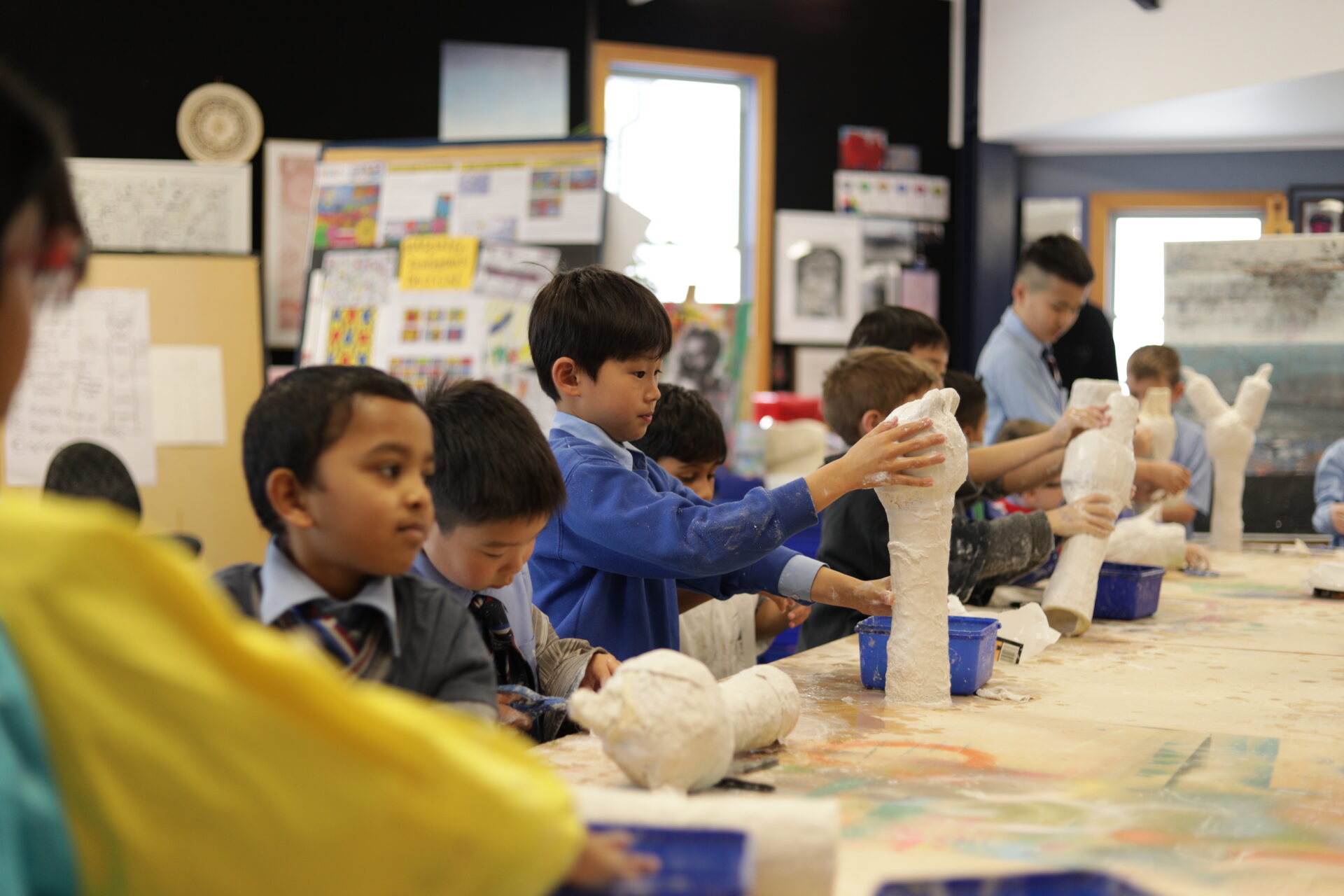 Students at Wellesley College in the art room creating sculptures, focused on shaping and designing